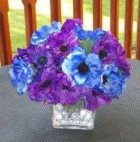 These centerpieces are silk flowers in square glass vases, created by Creative Edge Events (www.chebellaevents.com). The flowers are purple and blue anemones.