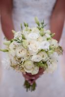 vintage bridal bouquet. A combination of white and ivory roses with white lisianthus and dashes of green lisianthus buds. Uneven, natural and organic type, wrapped with white satin ribbon. 