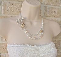 Mother of pearl natural shells, pale pink pearls and clear crystals have been united to form a tri-strand necklace with a handcrafted wire wrapped pendant that lies beautifully on the collar bone. Sparkle with this necklace for your walk down the aisle!