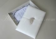 White invitation box with silk trim and lining. Padded in/exterior, elegant crown brooch embellishment with decent pearls and many crystal stones.