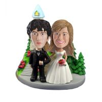 This custom bobblehead include a castle style church, green bush, rocky steps and a big gray base. The custom bobblehead groom is in back suit and black shinny leather shoes. The custom bobblehead bride is in traditional white dress with a bunch of rose i